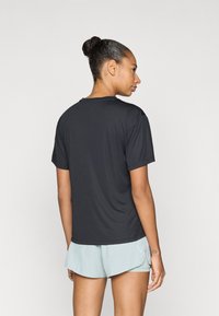 Μαύρο T-shirt με κοντά μανίκια και στρογγυλή λαιμόκοψη, κατασκευασμένο από απαλό, ελαφρύ ύφασμα. Φοριέται με ανοιχτόχρωμα μπλε σορτς, παρουσιάζοντας απλό σχέδιο.