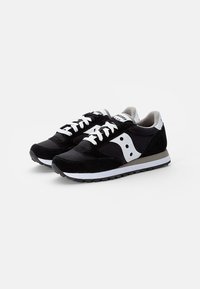 Černobílé sportovní boty s svrchním dílem ze suede a síťoviny, bílé tkaničky a texturovanou gumovou podrážkou s výraznými logovými detaily.