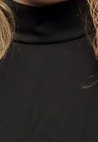 Top negro de cuello alto con una textura suave, que presenta un alto cuello. La vista en primer plano enfatiza el brillo de la tela y el diseño sin costuras.