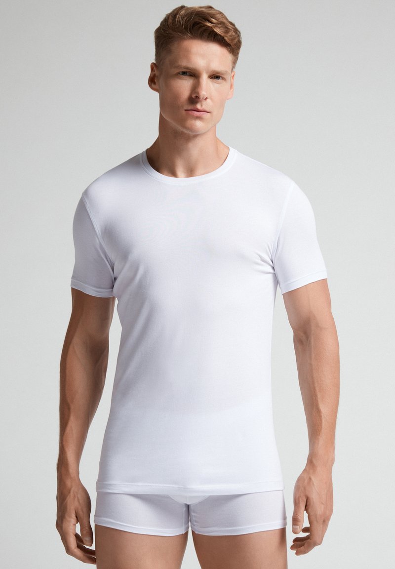 Weißes Kurzarm-T-Shirt aus glattem Stoff, mit rundem Halsausschnitt und enganliegender Silhouette, kombiniert mit weißen Boxershorts.