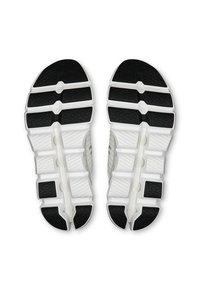Semelles de chaussures avec une base blanche et des sections en caoutchouc noir. Présente un design segmenté avec des grips texturés et une indentation centrale.