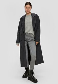 Koolgrijze wollen blend jas met een dubbelzijdig ontwerp, gecombineerd met een lichtgrijze gebreide trui en grijze slim-fit jeans, in combinatie met zwarte laarzen.