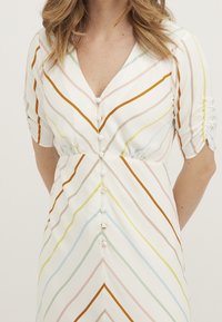 Randig klänning med V-halsskjärning och korta rynkade ärmar. Har horisontella och diagonala ränder i orange, rosa, grön och blå på en vit bakgrund.