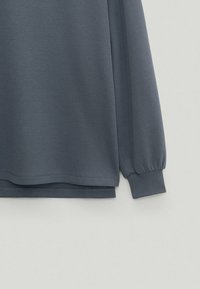 Long-sleeve gray top made of soft fabric, featuring a relaxed fit, cuffed sleeves, and a straight hem with a smooth texture.