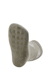 Grüne gestrickte Socke mit strukturiertem Gummigrip-Muster an der Sohle, geripptem Bündchen und weißem Schneeflockendesign. Am oberen Ende gewölbt.