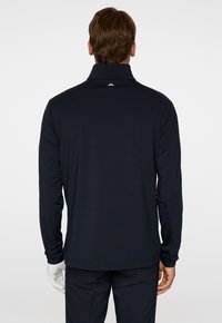 Polo shirt nero a maniche lunghe con colletto alto, tessuto liscio, design minimalista, con logo sul retro. Adatto per un abbigliamento casual.