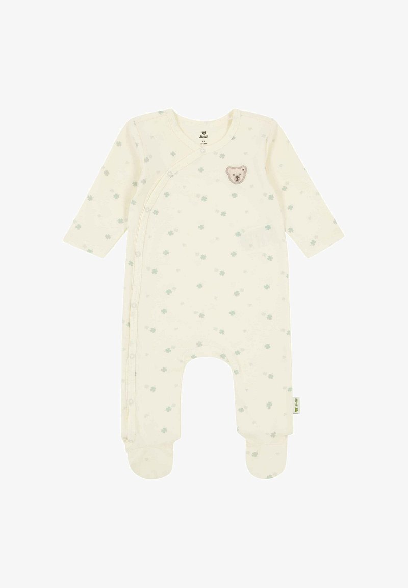 Kremowy kaftanik niemowlęcy z długimi rękawami, stopkami na nogach, drobnym zielonym nadrukiem koniczyny oraz małą naszywką z misiem na piersi.