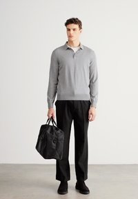 Pulover gri cu guler în V, pantaloni negri și geantă duffle neagră. Puloverul este tricotat, mulat; pantalonii sunt lejeri; geanta are detalii cu bretea și fermoar.