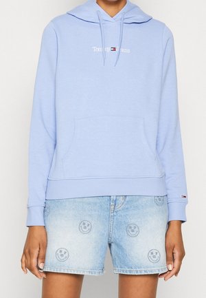 Haut à capuche bleu clair avec une poche avant et un logo brodé. Assorti à un short en denim avec des motifs de visages souriants. Matériaux doux et décontractés.