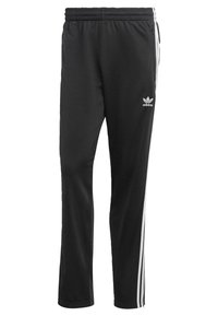 Pantalones deportivos negros con franjas laterales blancas, cintura elástica y logotipo de Adidas en el muslo izquierdo. Hechos de un tejido suave y transpirable.