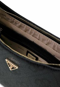 Interno di una borsa nera con texture, con una zip dorata, fodera beige e logo "GUESS" stampato. Include tasche per l'organizzazione.