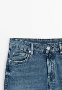 Jean denim bleu avec poches avant, passants pour ceinture, et fermeture à bouton métallique sur fond blanc.