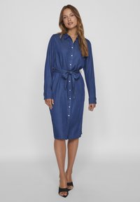 Denim srajčna obleka, z dolgimi rokavi, z pasom na sredini, s sprednjimi gumbi, temno modre barve, z bočnimi razporki in ravno silhueto.