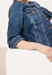 Jeansjacka i mörkblått med en något urblekt finish, med knappstängning, två bröstfickor och uppvikt ärmar.