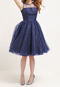Navy blue dress with a fitted bodice and a flared tulle skirt. Features sparkly details and a sheer neckline. Paired with silver heels.