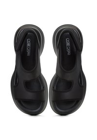 Černé sandály s otevřeným designem, obsahující vykrojené části, měkkou tkaninu a polstrovanou podrážku pro pohodlí. Minimalistický styl a elegantní linie.