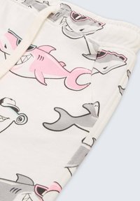 Shorts en coton avec une base blanche et des illustrations colorées de requins en rose, gris et noir, et une taille élastique ajustable.