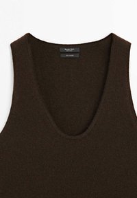 Canotta in cashmere marrone con scollatura ampia. Tessuto morbido, bordi a coste e etichetta con informazioni sul marchio e sul materiale.