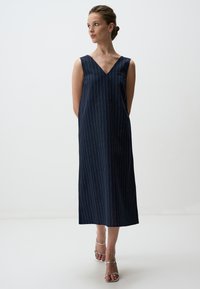 Navyblauwe, mouwloze jurk met een V-hals, verticale streepjes en een knielange zoom; gladde stof met een relaxte pasvorm.