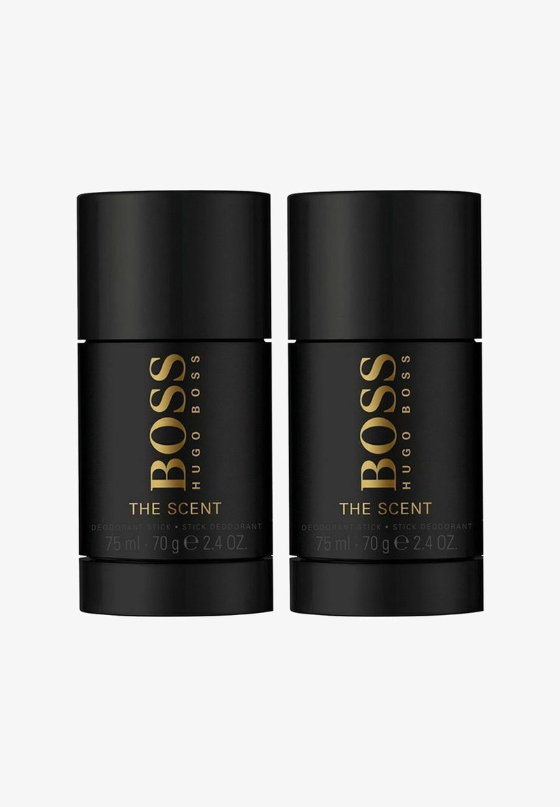Kaksi mustaa tikkudeodoranttia, kumpikin 75 ml, joissa on kultateksti "BOSS THE SCENT". Tyylikäs sylinterimäinen muotoilu, jossa on matta pinta.