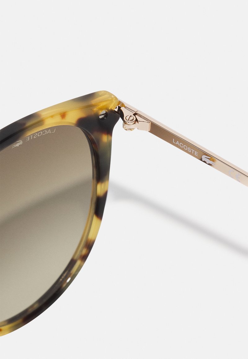 Occhiali da sole tartarugati con montatura in metallo dorato. Lenti rotonde con gradazione sfumata. Presentano dettagli del marchio sulla tempia.