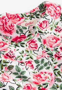 Floral shirt with a white background, featuring pink roses and green leaves, a collared neck, and white buttons. Label reads "Cath Kids London."
