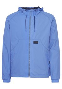 Jachetă cu glugă de culoare bleu deschis, fabricată dintr-un material neted, rezistent la apă. Dispune de un fermoar frontal, mansete elastice și două buzunare laterale.