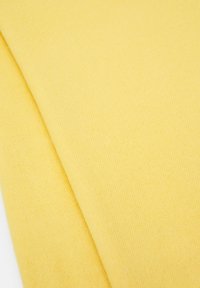Tissu jaune avec une texture douce et un motif en fines côtes, plié soigneusement. Teinte lumineuse et couleur uniforme.