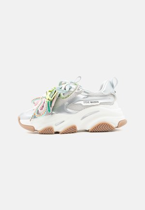 Pantof sport alb, robust, cu panouri din plasă argintie, șireturi multicolore, talpă din cauciuc bej și inscripția "Steve Madden" pe lateral.