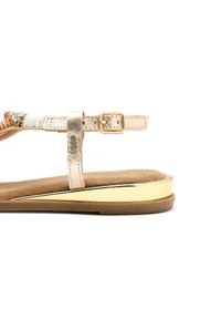 Sandal in metallo dorato con un cinturino testurizzato adornato di perline e dettagli. Plantare imbottito marrone e suola a profilo basso con finitura dorata.