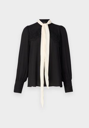 Svart långärmad blus med en krämfärgad slips, som har spetsdetaljer på oket och ärmarna, samt en mjuk, flödande textur.