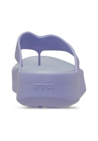 Fioletowe klapki Crocs mają teksturowany pasek, lekką konstrukcję oraz podniesioną podeszwę z wytłoczonym logo. Gładka wkładka zapewnia komfort noszenia.