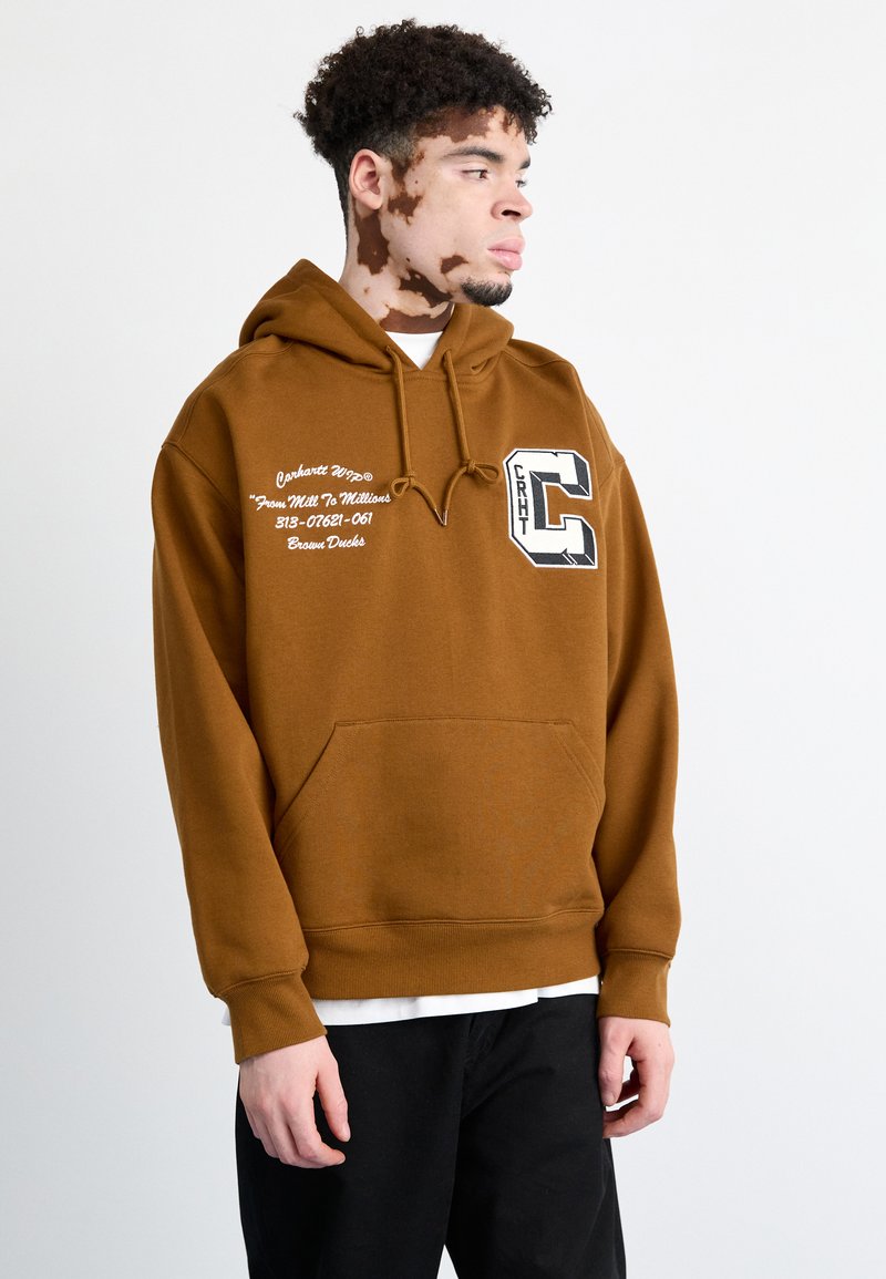 Sudadera marrón con capucha, con un bolsillo tipo canguro, texto blanco y una gran gráfica de "C" en la parte frontal. Puños y dobladillo acanalados.