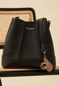 Black leather bucket bag with textured surface, gold hardware, and a keychain tag with dual rings. Logo embossed on the front.