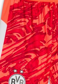 Shorts orange avec des motifs abstraits rouges, taille élastique, et un logo circulaire noir avec "BVR" en bas à gauche.