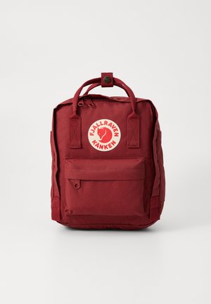 Zaino in nylon rosso con doppi manici, tasca frontale con zip e logo circolare Fjällräven. Design compatto e rettangolare con spallacci regolabili.