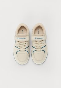 Beez sneakers, mille tekstuuriga, siniste aktsentidega, lipsu kinnitusega ja takjakinnitusega. Championi logo küljes ja keeles.