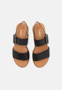 Zwarte leren sandalen met twee brede banden, verstelbare gesp en een tan leren voetbed met de merknaam "Gabor" erop gedrukt.