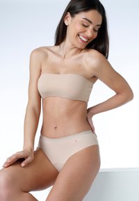 Top bandeau beige abbinato a slip bikini coordinato, caratterizzato da una texture liscia e da un sottile dettaglio del logo. Design minimalista.
