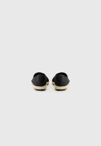 Svart lerret espadriller med en vevd jutesåle. Rund form, minimalistisk design, glatt tekstur, ingen synlige detaljer eller maskinvare.