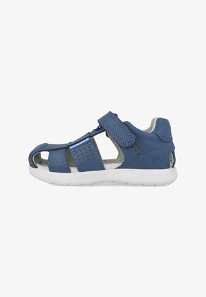 Sandalia azul con diseño abierto. Presenta cuero perforado, correas de Velcro y una suela de goma blanca. Acentuada con pequeños patrones cuadrados.