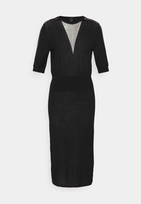 Robe noire longueur genou avec manches mi-longues et un panneau triangulaire en résille transparente au niveau de la poitrine.