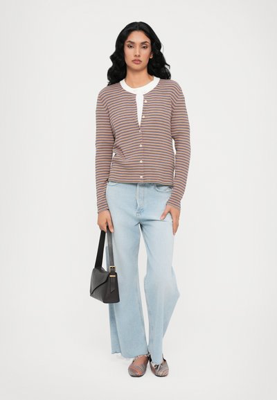 Striped cardigan in brown, white, and orange, featuring a button-up front and round neckline. Paired with light blue wide-leg jeans and patterned shoes.