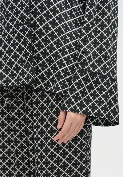 Μαύρο και λευκό σετ lounge με γεωμετρικό σχέδιο, χαλαρές μανίκες και λεία, μαλακή υφή υφάσματος.