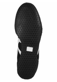 Black rubber outsole with circular grip pattern, featuring white accents and branding. The shoe has a rounded shape and a textured surface.