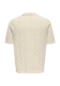 Maglietta a maniche corte in maglia color beige chiaro con un motivo testurizzato e colletto classico. Presenta polsini e fondo a costine.