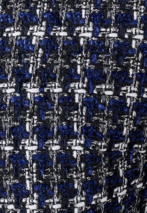 Primer plano de tela tejida con textura, con hilos negros, azules, blancos y plateados metálicos que crean un patrón parecido a una cuadrícula.