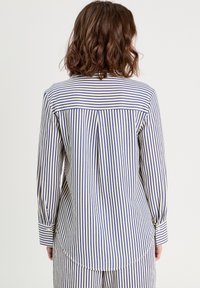 Chemise à rayures à manches longues avec de fines rayures bleues et blanches, poignet boutonné et un détail de plis au dos pour plus de fluidité.