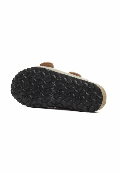 Calzature con suola in gomma nera caratterizzata da motivi circolari in rilievo, tomaia in tessuto beige e cinturini in pelle marrone.