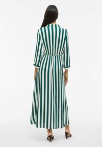 Robe longue rayée verte et blanche avec un col montant, des manches trois-quarts et une taille cintrée, descendant jusqu'aux chevilles.